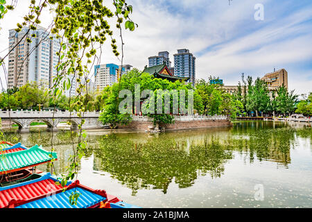 Urumqi Renmin Gongyuan People's Park le Pavillon du Lac à couper le souffle avec des gratte-ciel à l'arrière-plan sur un ciel bleu ensoleillé Jour Banque D'Images