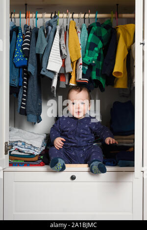 Vêtements pour enfants en souriant hiden penderie remplie de vêtements de couleur Banque D'Images