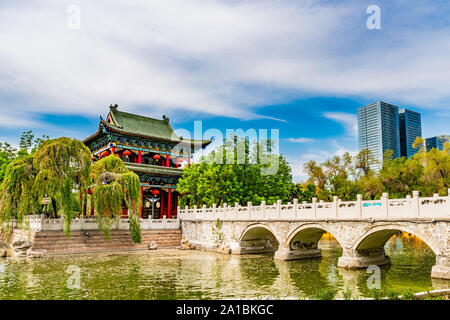 Urumqi Renmin Gongyuan People's Park le Pavillon du Lac à couper le souffle avec des gratte-ciel à l'arrière-plan sur un ciel bleu ensoleillé Jour Banque D'Images