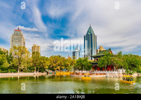 Urumqi Renmin Gongyuan People's Park le Pavillon du Lac à couper le souffle avec des gratte-ciel à l'arrière-plan sur un ciel bleu ensoleillé Jour Banque D'Images