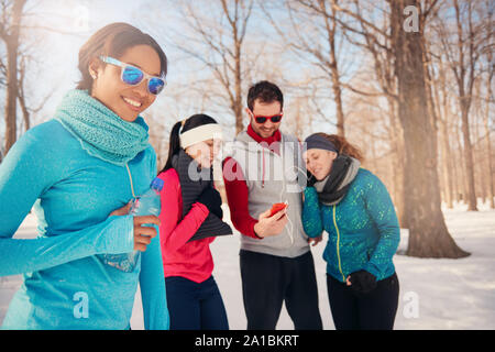 Groupe d'amis à écouter de la musique dans la neige en hiver Banque D'Images