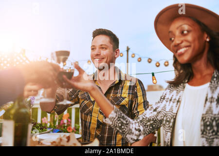 Groupe d'amis divers dîner et un verre de vin en plein air en milieu urbain Banque D'Images