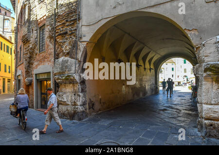 L'une des quatre portes cintrées de la Piazza dell'Anfiteatro dans le centre historique de Lucca avec les gens et les touristes en été, Toscane, Italie Banque D'Images