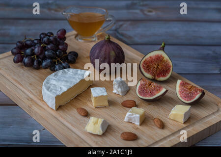 L'entrée au dessert - vin de figues, fromage brie, raisins rouges, miel servi sur une planche en bois Banque D'Images