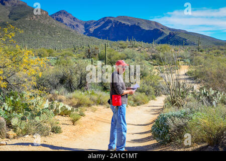 Un randonneur est préparée avec chapeau, lunettes de soleil et de l'eau tout en marchant un sentier à l'intérieur de la zone de loisirs de Sabino Canyon dans les montagnes près de Santa Catalina Banque D'Images