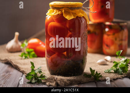 Des bocaux de Tomates Marinées sur un fond de bois rustique. Décapés et produit en conserve. Suivant autres pour la cuisson Banque D'Images