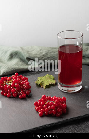 Jus de fruits rouges de viburnum dans un verre sur un fond clair. Près de viburnum baies, et tissu en lin. L'alimentation saine Banque D'Images