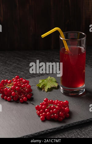 Jus de fruits rouges de viburnum dans un verre avec un tube sur un fond sombre. Près de viburnum de baies. L'alimentation saine Banque D'Images