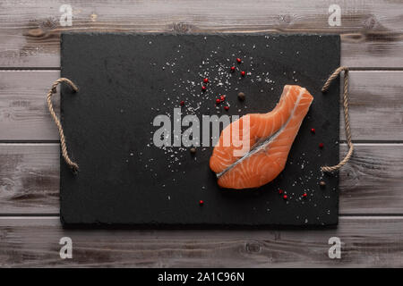 Pavé de saumon cru. Sur une carte avec le poivron rouge et le sel. Alimentation saine. Vue d'en haut. Fond de bois Banque D'Images