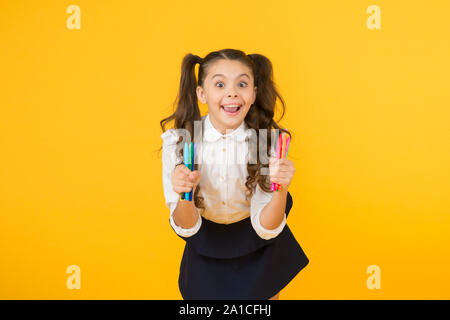 Faire de l'art sur la première journée d'école. Happy School Child holding marqueurs sur fond jaune. Petite fille profiter de leçons de dessin à l'école. L'école de pensée créative. Banque D'Images