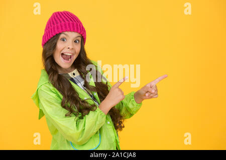 Choisissez entre plus mignonne et la plus branchée. Des cheveux longs de fille fond jaune. Saison froide concept. Accessoire de mode d'hiver. Petit enfant portant chapeau chaud. Kid girl porter chapeau tricoté. Bonnet hiver accessoire. Banque D'Images