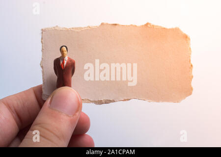 Main tenant une figurine homme placé sur morceau de papier déchiré Banque D'Images