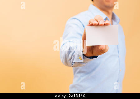 Close up of Businessman showing main carte blanche vide dans l'arrière-plan jaune vif avec copie espace. Nom carte vierge pour ajouter du texte Banque D'Images