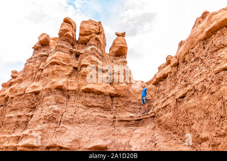 Escalade homme debout sur des rochers de grès Hoodoo au camping dans paysage de désert en parc d'état de Goblin Valley Banque D'Images