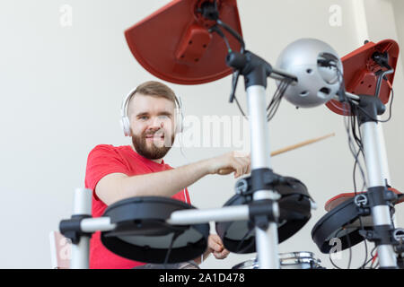 Les émotions, les passe-temps, de musique et de personnes concept - batteur émotionnel joue de la batterie électronique. Banque D'Images