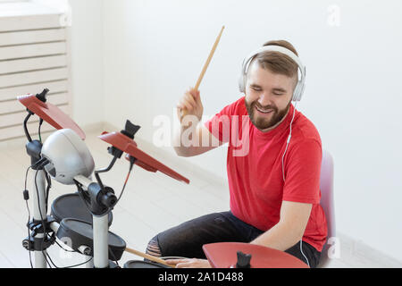 Les émotions, les passe-temps, de musique et de personnes concept - batteur émotionnel joue de la batterie électronique. Banque D'Images