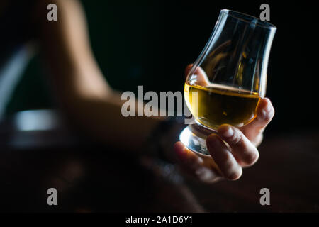 Gros plan d'une main d'attraper un verre whisky Glencairn. Banque D'Images