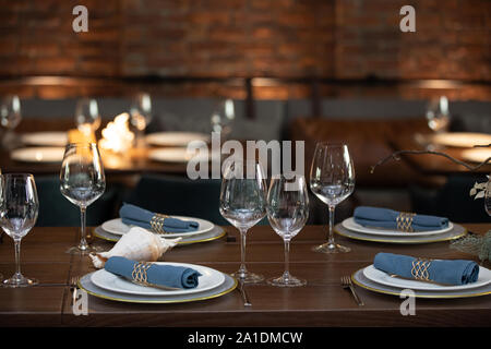 Table en bois servi avec Assiettes, fourchettes, cuillères, verres, serviettes de table bleu dans le restaurant Banque D'Images