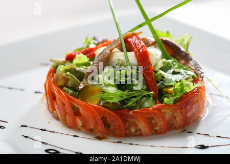 Salade gourmande avec les anchois et le fromage, tomate et laitue mélangée sur. Banque D'Images