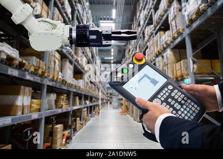 Ingénieur avec télécommande d'appareil. Robot de programmation avec bras robotique. Smart factory Banque D'Images