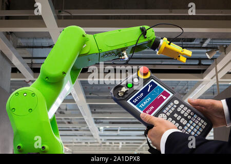 Ingénieur avec télécommande d'appareil. Robot de programmation avec bras robotique. Smart factory Banque D'Images