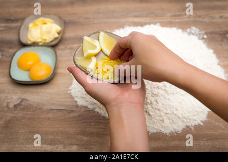 Femme donnant le zeste de citron sur une pâte crue pour produits de boulangerie faits maison, biscuit ou pâte à gâteau Banque D'Images