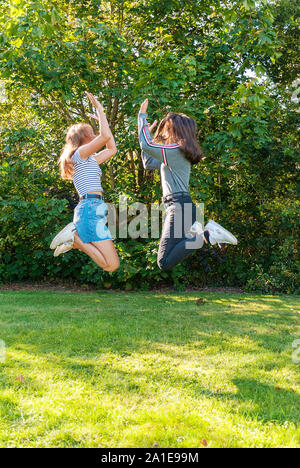 Deux adolescents Jeunes filles sautant dans un parc en été. S'amuser en vacances. Heureux les amis de passer du temps ensemble. L'amitié. Banque D'Images