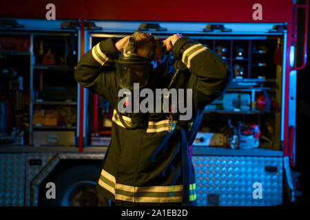 Image de fireman putting on masque à gaz sur fond d'incendie à la caserne. Effet néon Banque D'Images