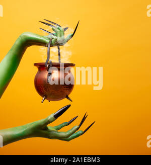 Image de deux mains troll vert avec chapeau melon vide sur fond orange Banque D'Images