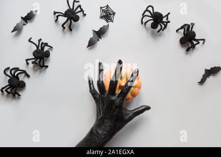 Araignée Halloween, citrouille, chauve-souris, femme les mains couvertes de peinture noire avec des décorations sur fond gris. Mise à plat, vue du dessus. Compo Halloween créatif Banque D'Images