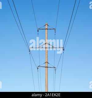 Pilier en béton, des lignes de transport d'électricité avec de l'acier traverse, isolateurs en porcelaine et les fils à haute tension sur un fond de ciel bleu clair Banque D'Images