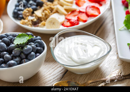 Le yogourt dans un bol en verre avec petit déjeuner sain sur la table Banque D'Images