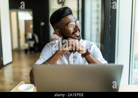 Beau mâle qualifiés d'étudiants de l'école en ligne de programmation qu'il pratique de l'exercice dans le codage de la saisie sur clavier d'ordinateur portable assis dans cafe Banque D'Images