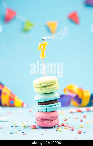 7ème 7ème carte d'anniversaire avec une bougie soufflée dans macarons colorés et paillettes. Maquette de la carte. Banque D'Images