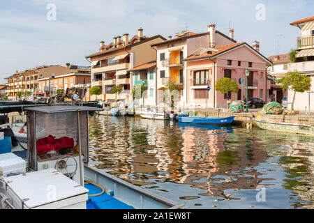 22 juillet 2019 - Grado, ITALIE - bâtiments résidentiels de couleur et de bateaux dans la lumière au coucher du soleil sont mirror reflète dans l'eau de mer du port de Grado Banque D'Images