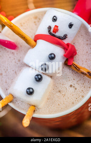 Bonhomme guimauve de fondre dans le chocolat chaud en rouge la coupe de fête. Banque D'Images