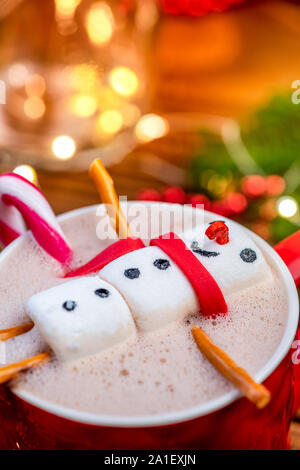 Bonhomme guimauve de fondre dans le chocolat chaud en rouge la coupe de fête. Banque D'Images