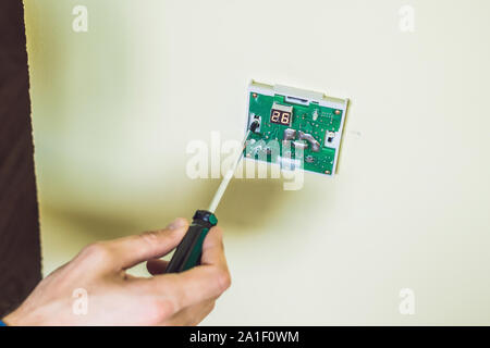 Electricien installation d'un thermostat électrique dans une maison neuve. Banque D'Images