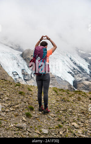 Randonnées girl à Hohtürli avec l'Oeschinensee au loin dans les nuages brumeux lors d'une randonnée Banque D'Images