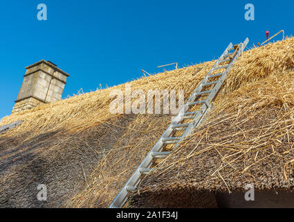 Outils sur le toit d'un village de chaume chalet comme il est en cours de réparation et de renouvellement Banque D'Images