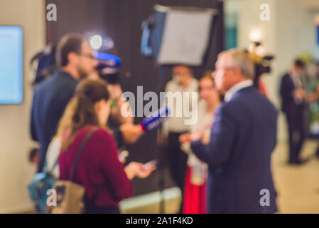 Photo floue. Les journalistes ont interviewé un homme. Microphone de l'appareil photo Banque D'Images