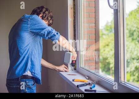 L'homme en chemise bleue n'installation de la fenêtre. Banque D'Images