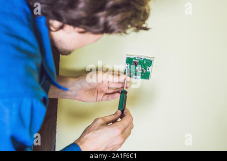 Electricien installation d'un thermostat électrique dans une maison neuve. Banque D'Images