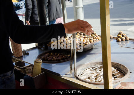Istanbul, Turquie, le 07 mars 2019 : détail de vendeur de rue derrière la rue traditionnel panier distributeur holding tongs préparer chestnut grillé Banque D'Images