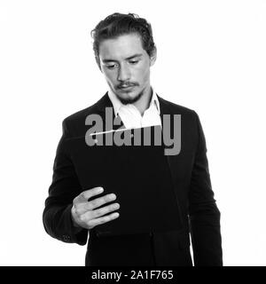 Studio shot of young handsome businessman reading sur presse-papiers isolés contre fond blanc Banque D'Images