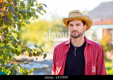 Beau cowboy, portrait d'un agriculteur dans son jardin. Un homme dans un chapeau de cowboy. Banque D'Images