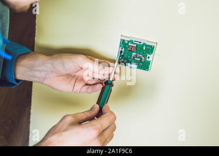 Electricien installation d'un thermostat électrique dans une maison neuve. Banque D'Images