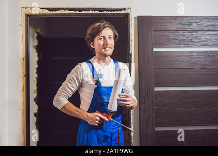 Handyman installation porte avec une mousse de montage dans une chambre. Banque D'Images