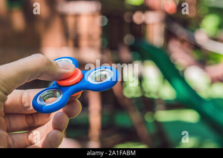 Garçon jouant avec fidget spinner. Spinner spinning enfant dans l'aire de jeux. Arrière-plan flou. Banque D'Images