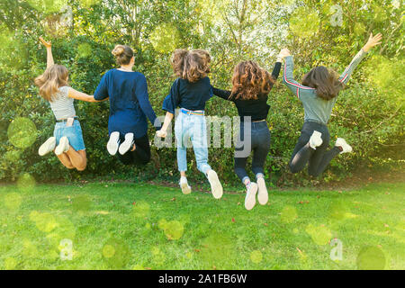 Groupe d'Adolescents Jeunes filles sautant dans un parc en été. S'amuser en vacances. Heureux les amis de passer du temps ensemble. L'unité de la diversité. L'amitié. Banque D'Images